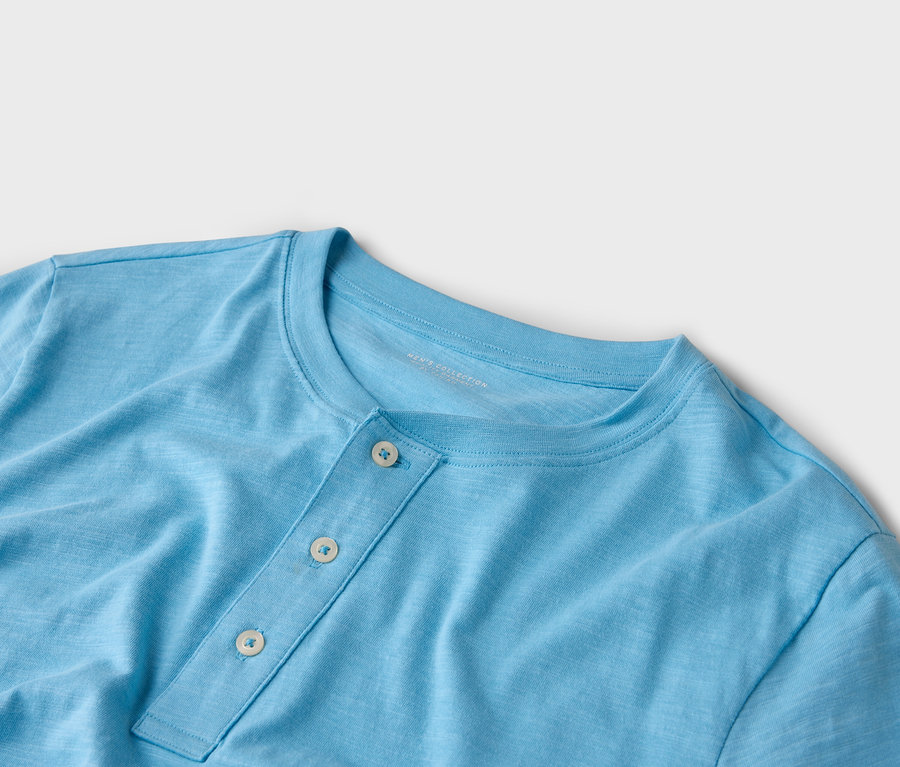 Detail modrého trička Henley se třemi knoflíky.