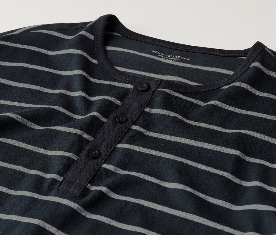 Detailní záběr na tmavě modré tričko Henley s dlouhým rukávem, šedými pruhy a třemi knoflíky.