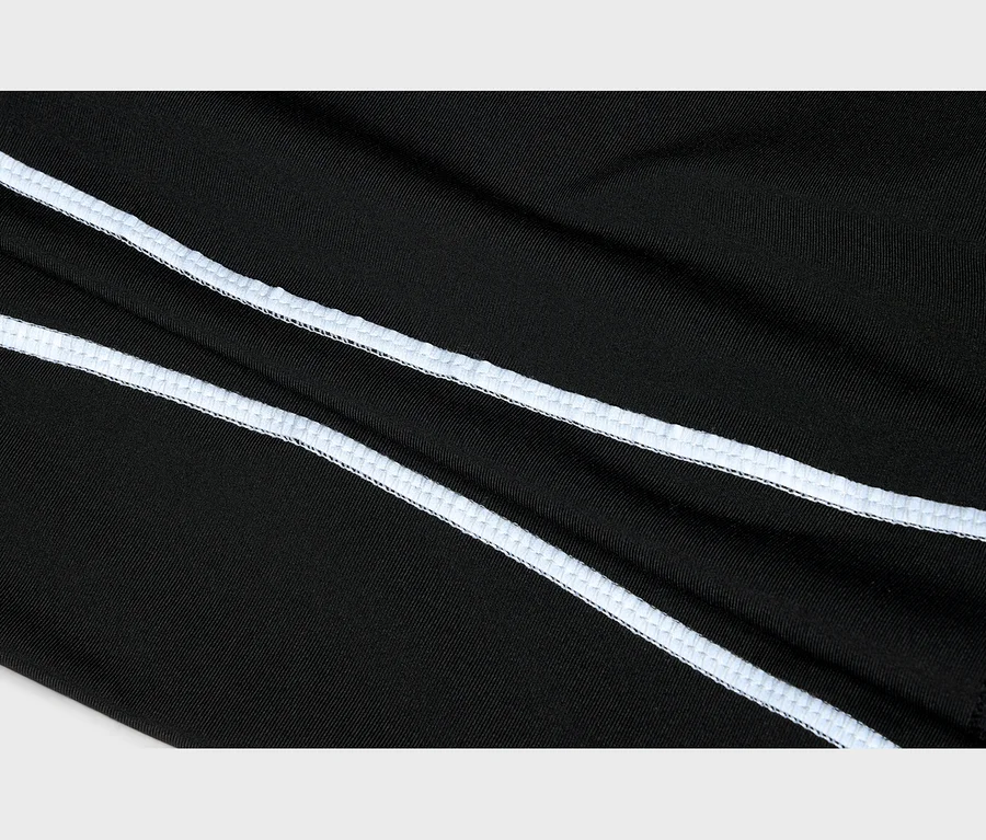 Detail černého materiálu se dvěma paralelními bílými overlockovými švy vedoucími diagonálně.