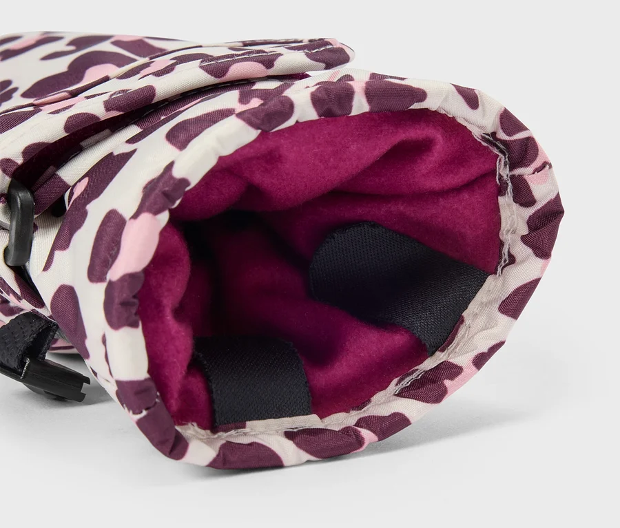 Detail rukavice s leopardím vzorem v bílé, růžové a fialové barvě, ukazující její tmavě růžovou fleecovou podšívku a černý popruh na boku.