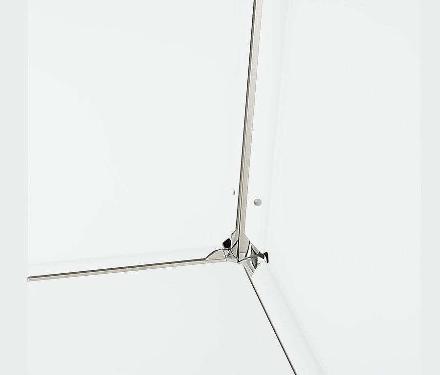 Detail rohu bílé kovové odkládací skříňky se 2 přemístitelnými výklopnými dvířky.