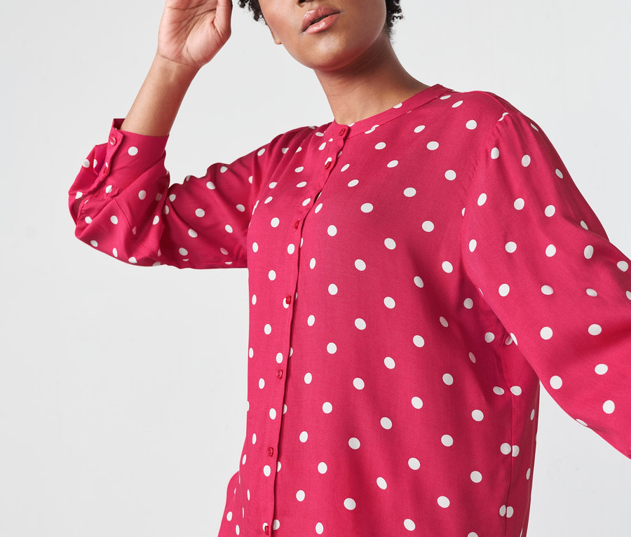 Žena pózuje v puntíkované tkané halence.