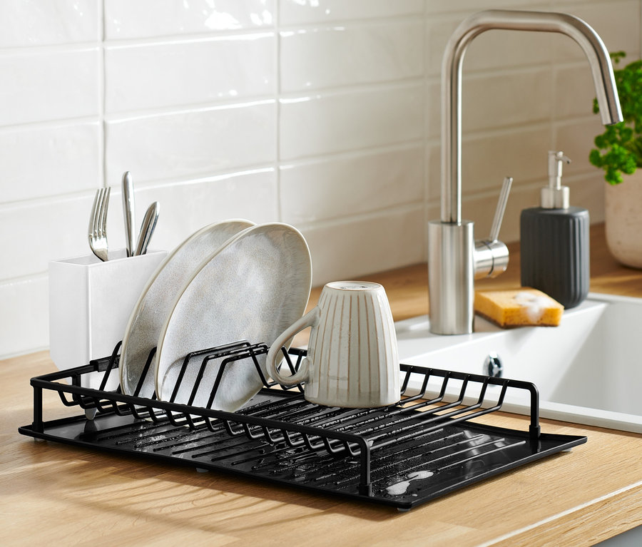 Černý odkapávač na nádobí s odkapávací podložkou na lince s nádobím.