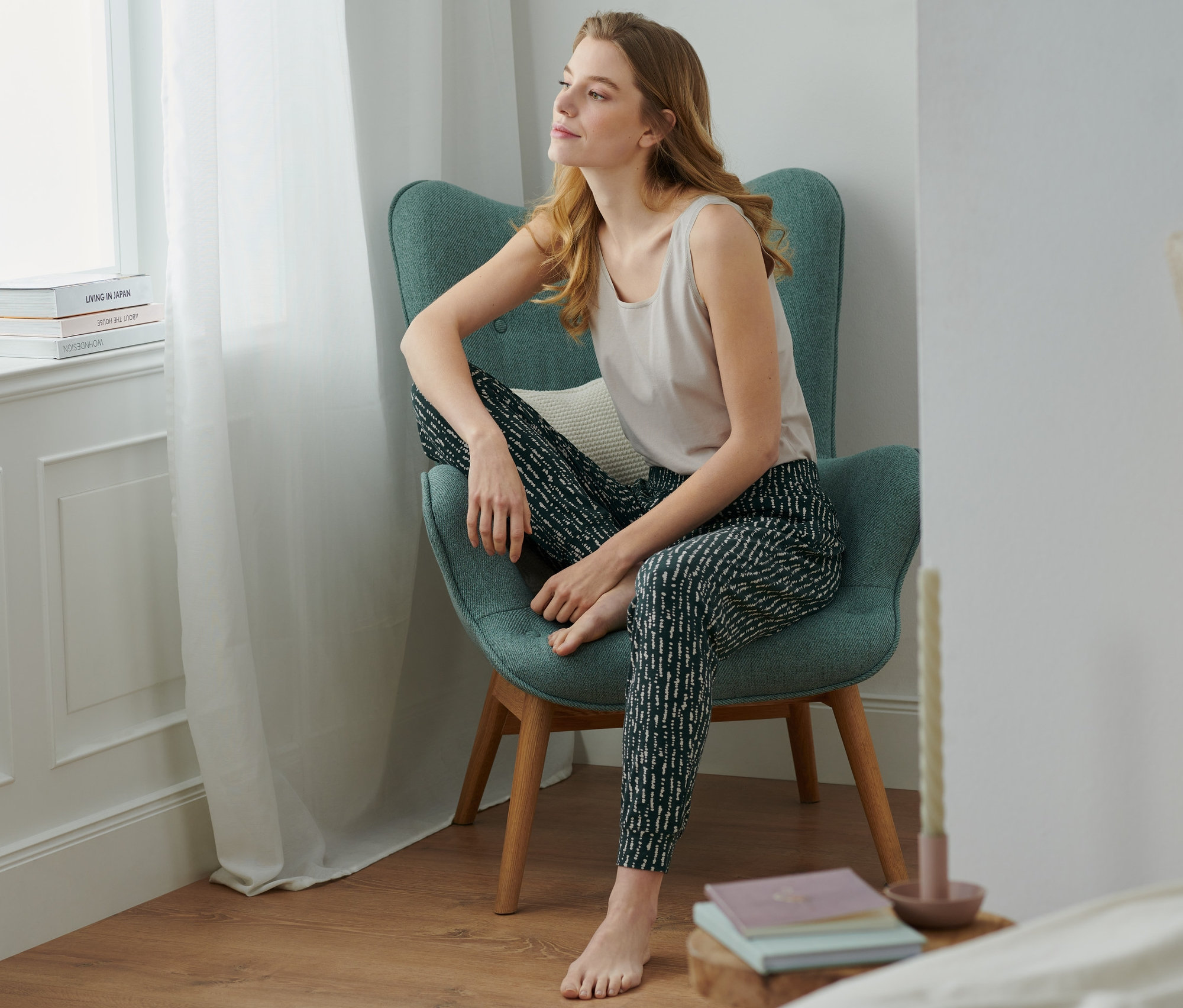 Žena sedí v křesle a má na sobě pohodlné kalhoty.