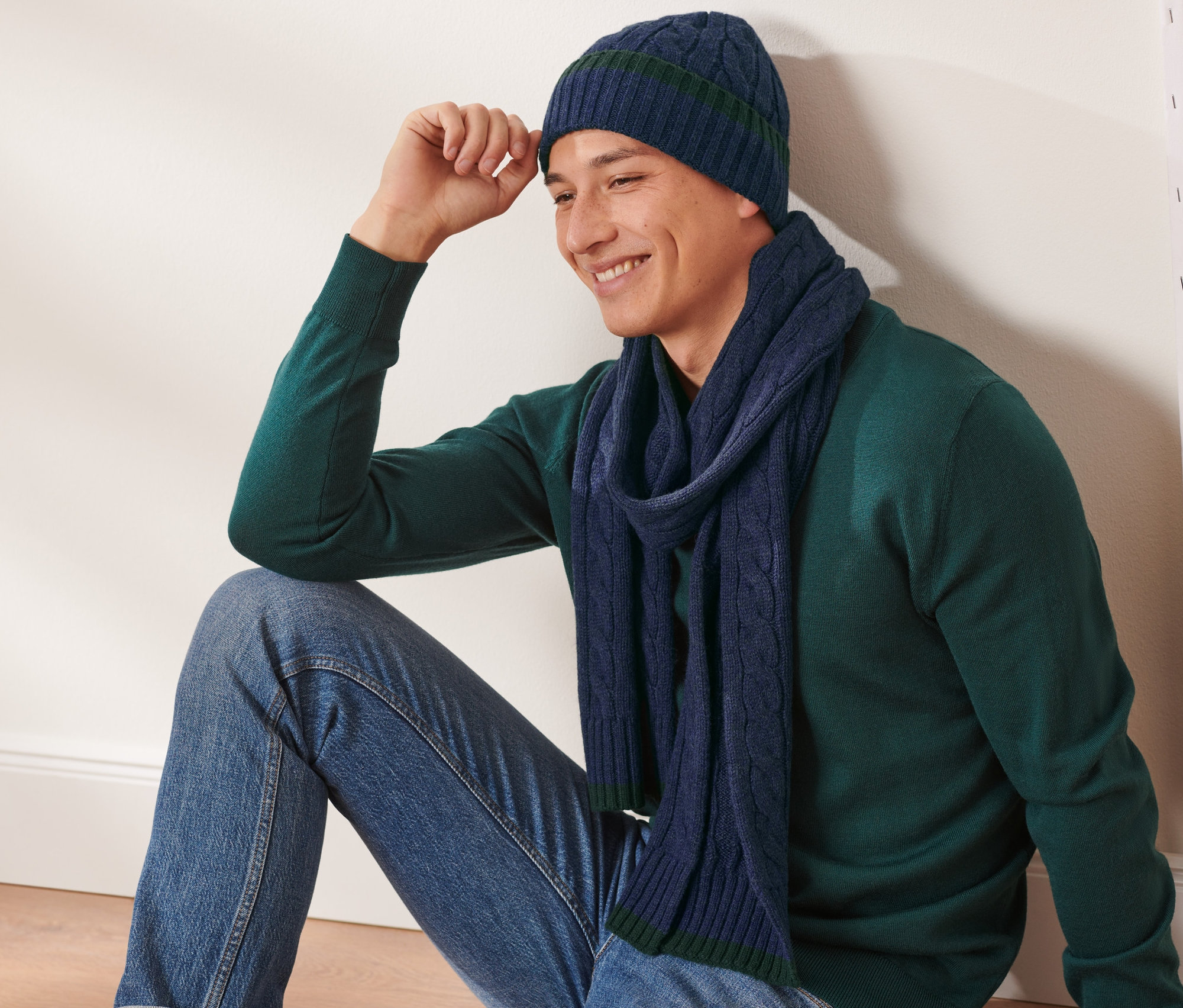 Muž sedí a má na sobě soupravu čepice a šály.
