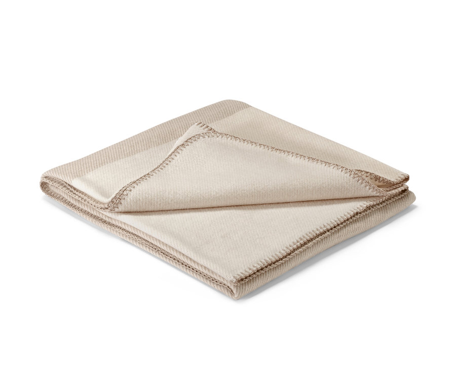 Béžová deka s ozdobným lemem.