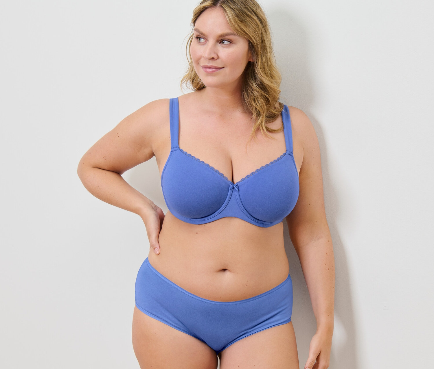 Žena pózuje v modré podprsence s kosticemi a kalhotkách.