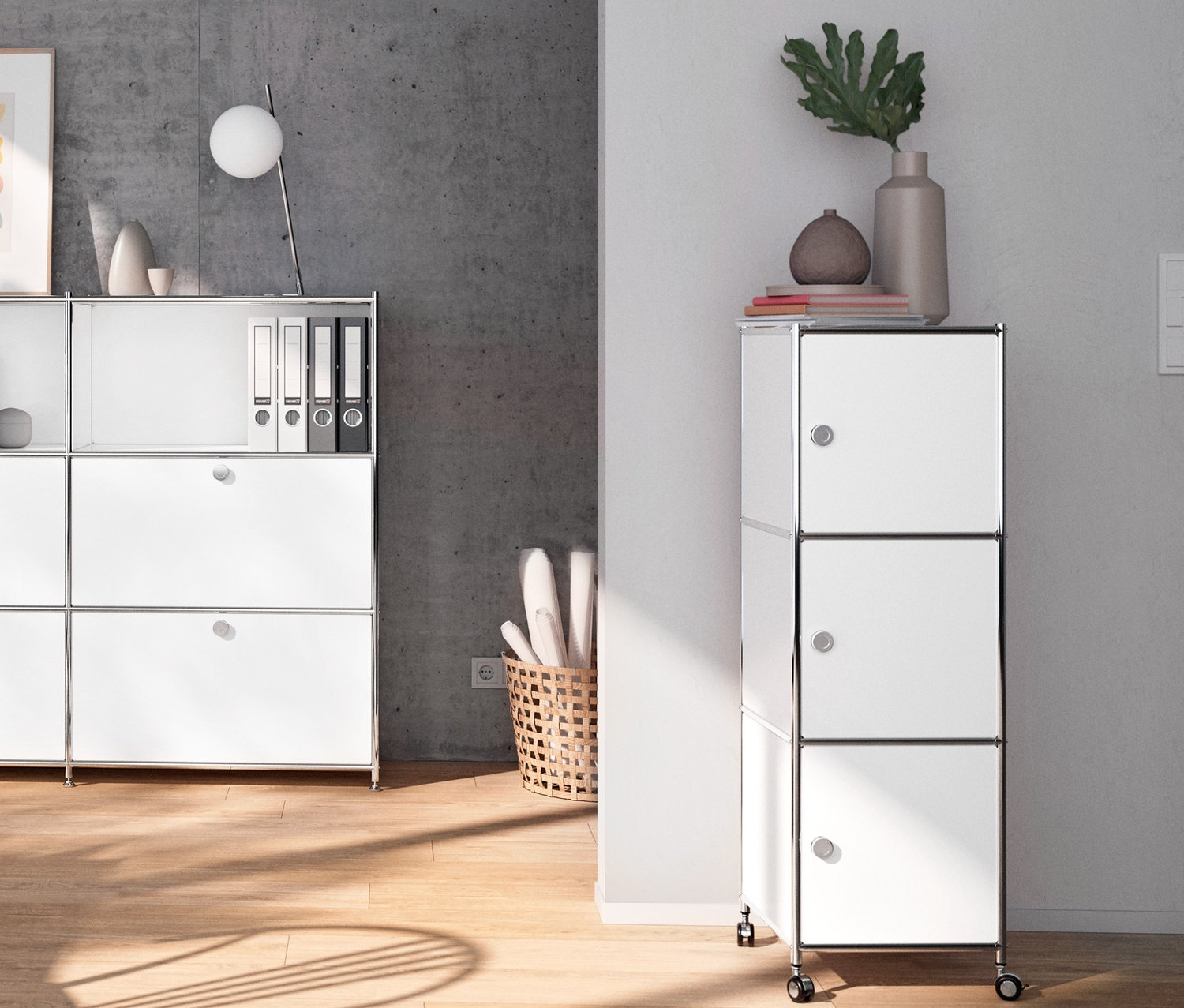 Interiér s bílou kovovou komodou CN3 s výklopnými dvířky, bílým kovovým psacím stolem CN3 s výklopnými dvířky, bílým kovovým kontejnerem na kolečkách CN3 a chromovanou kovovou stolní lampou.