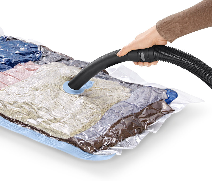 Ruka drží hadici vysavače na vakuovém úložném pytli, 2 ks, horizontální.