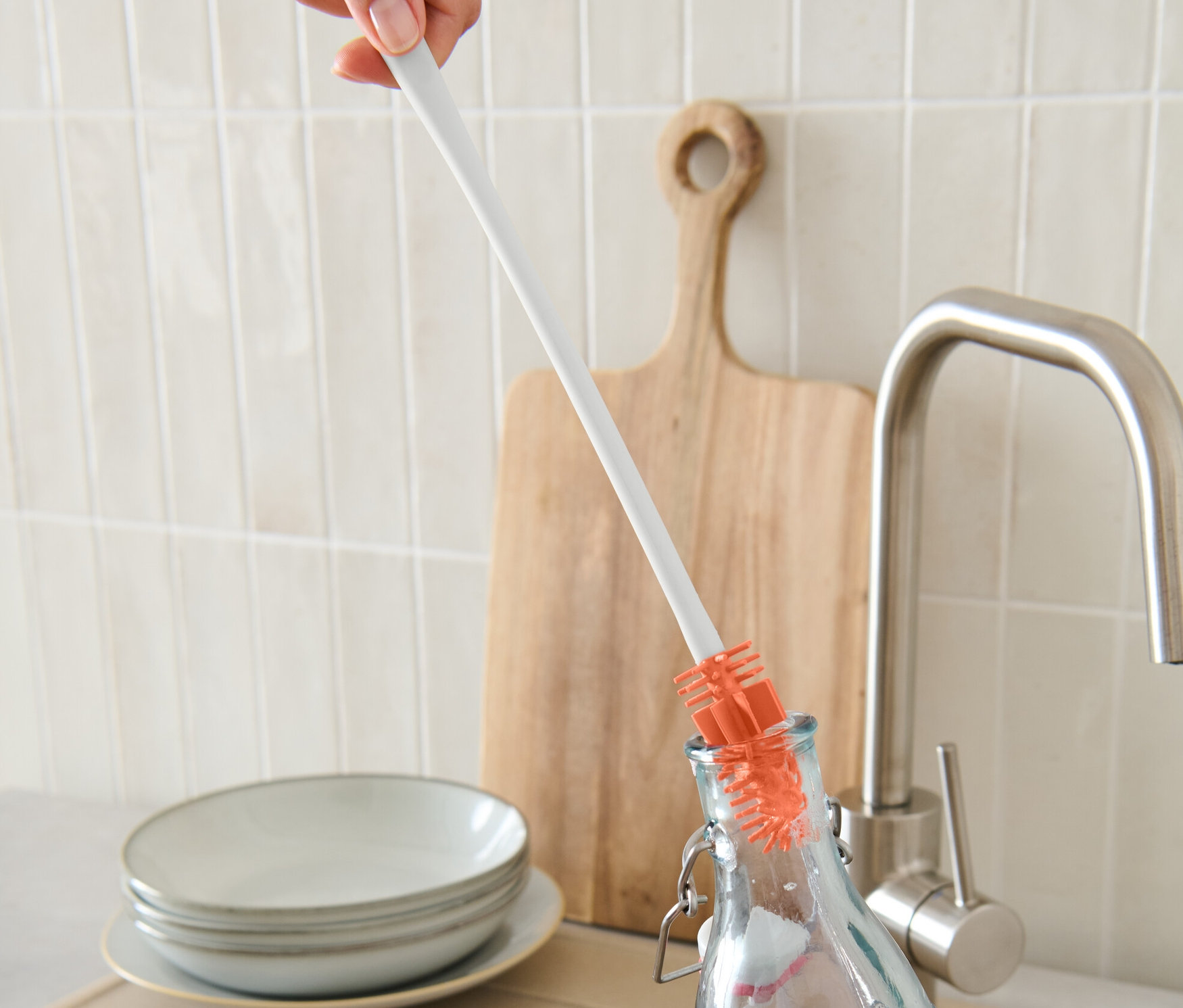 Ruka myje láhev pomocí štětky na láhve.
