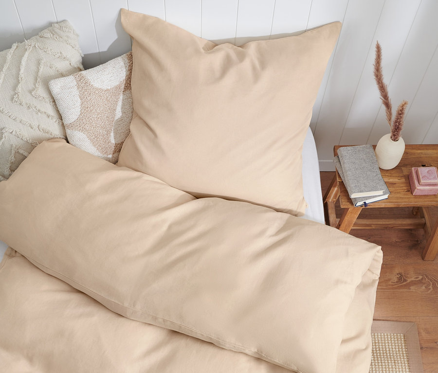 Béžové povlečení ze sepraného lnu, standardní velikosti, na dvojlůžko a nadměrné velikosti na posteli s bílým čelem.