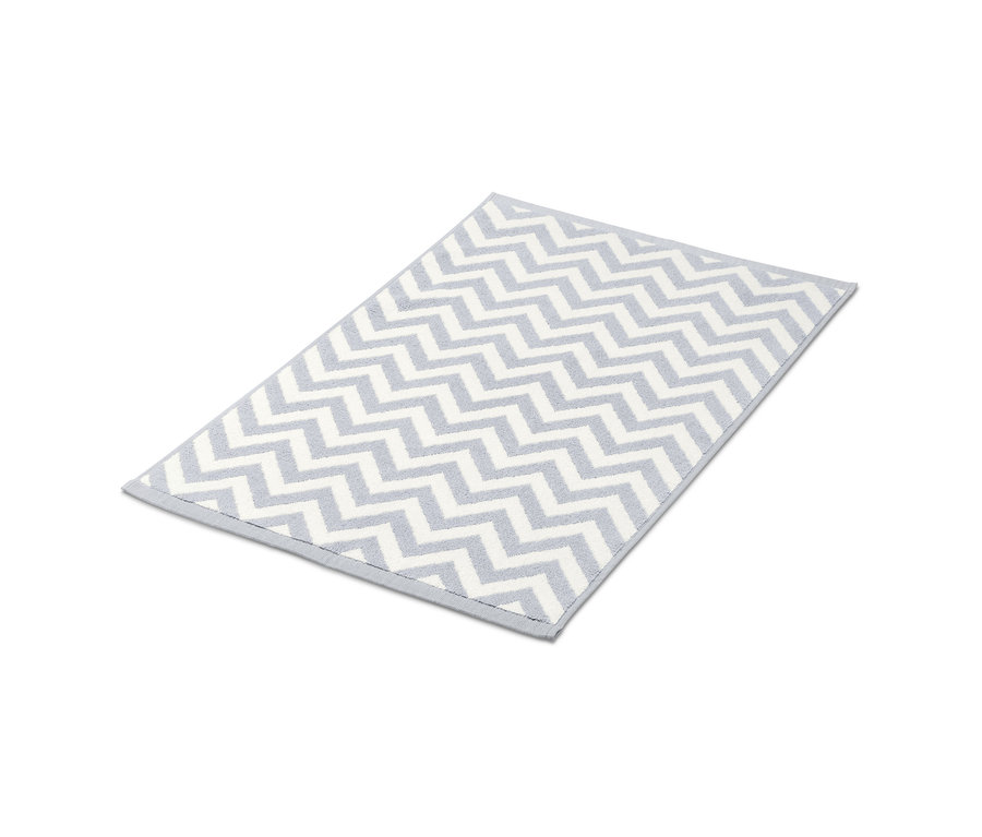 Šedo-bílá předložka do sprchy s cikcakovým vzorem.