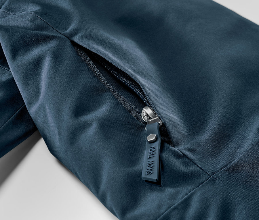 Detail námořnicky modré lyžařské bundy se zipem.
