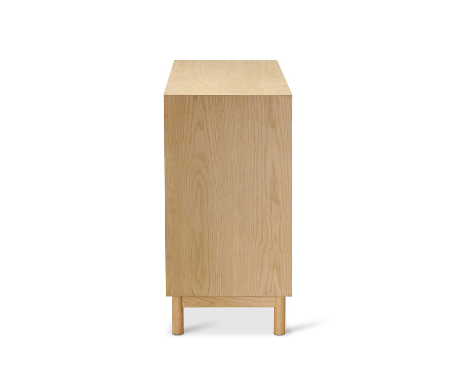 Komoda z jasanového dřeva s dekorativními čely dvířek.