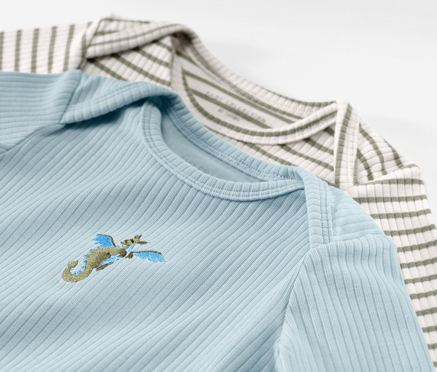 Dvě dětská body s dlouhým rukávem s žebrovanou strukturou, světle modré s výšivkou a zelenobílé pruhované.