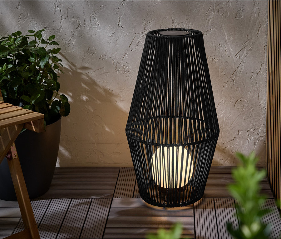 Velká solární lucerna s textilním výpletem stojí na terase.