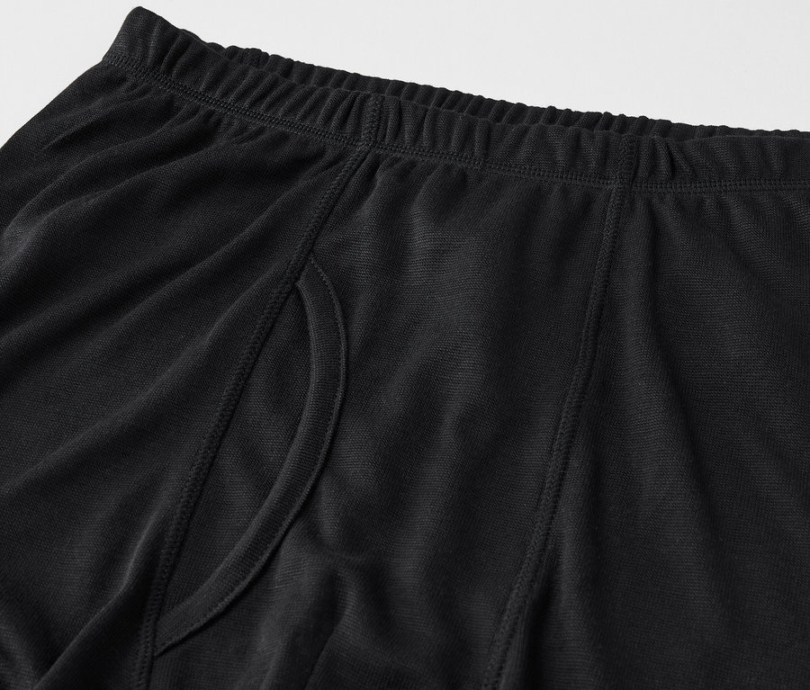 Detail černých pánských boxerek s elastickým pasem a bočním rozparkem.