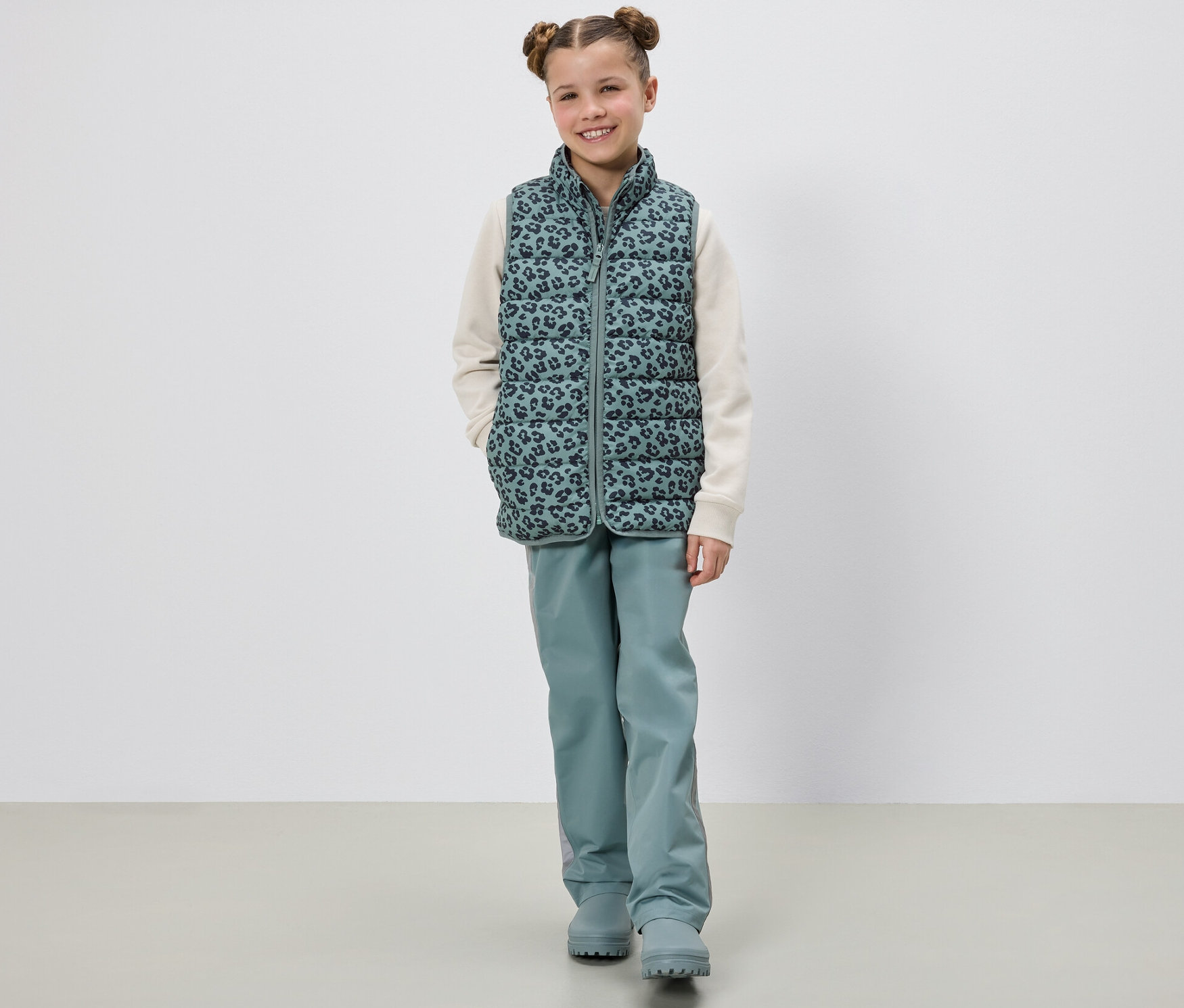 Dívka pózuje v dětské prošívané vestě.