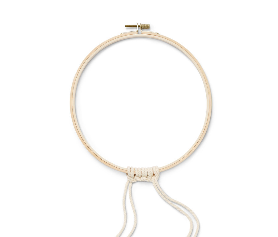 Sada na výrobu drhaného zimního věnce: Dřevěný kruh s knoflíkem a připevněnými krémovými provázky.