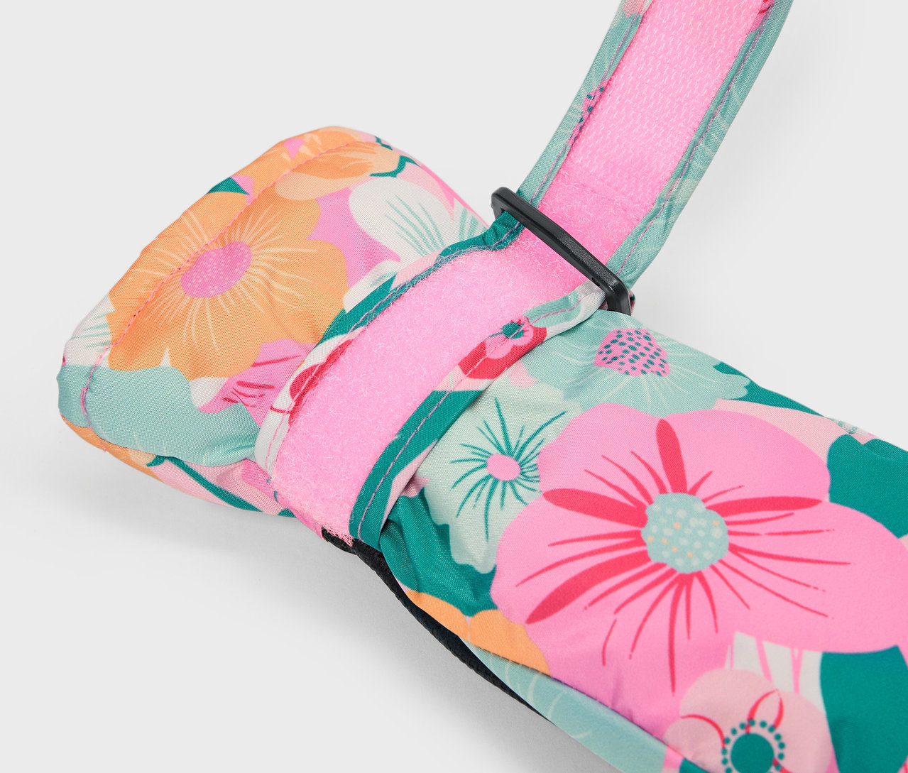 Detail pestrobarevné květinové lyžařské rukavice s růžovým páskem.