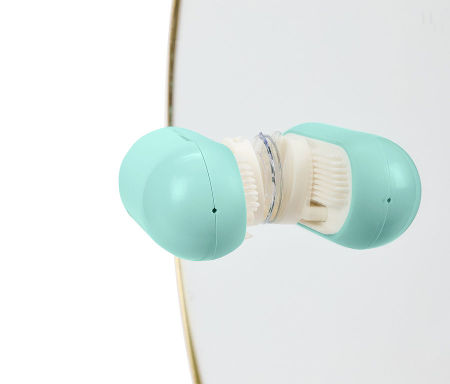 Detail of an open, light blue cleansing brush with white bristles.