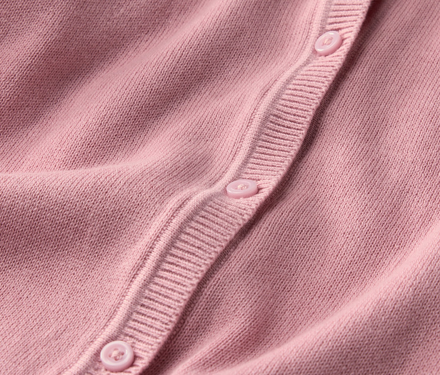 Detail dívčího pleteného svetru s knoflíky.