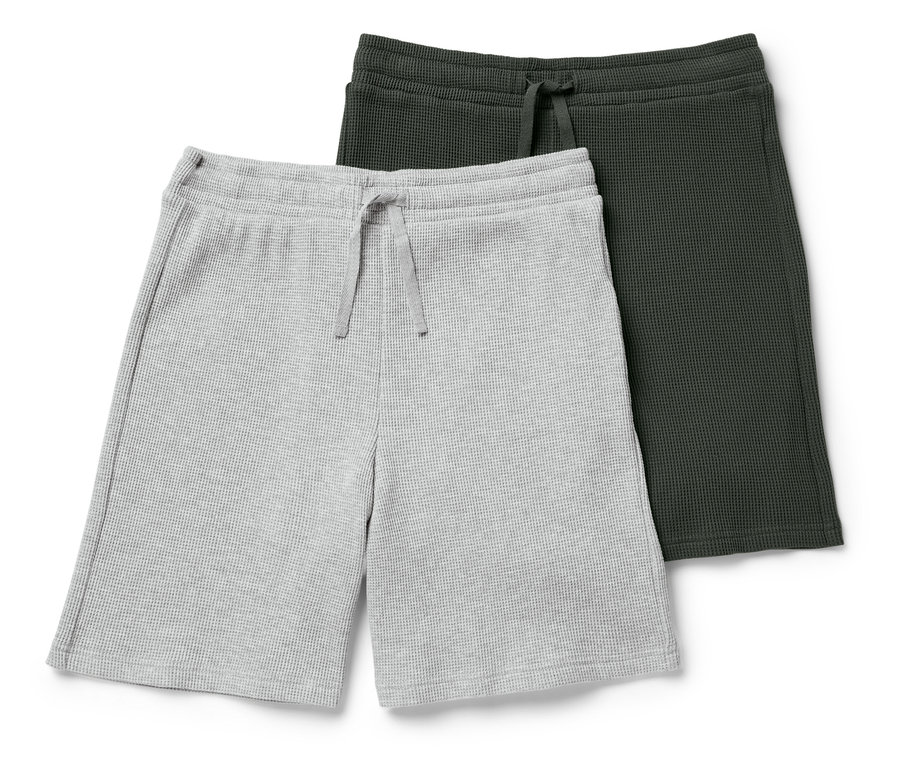 Dvoje pletené šortky, jedny šedé a jedny tmavě zelené, leží na sobě.