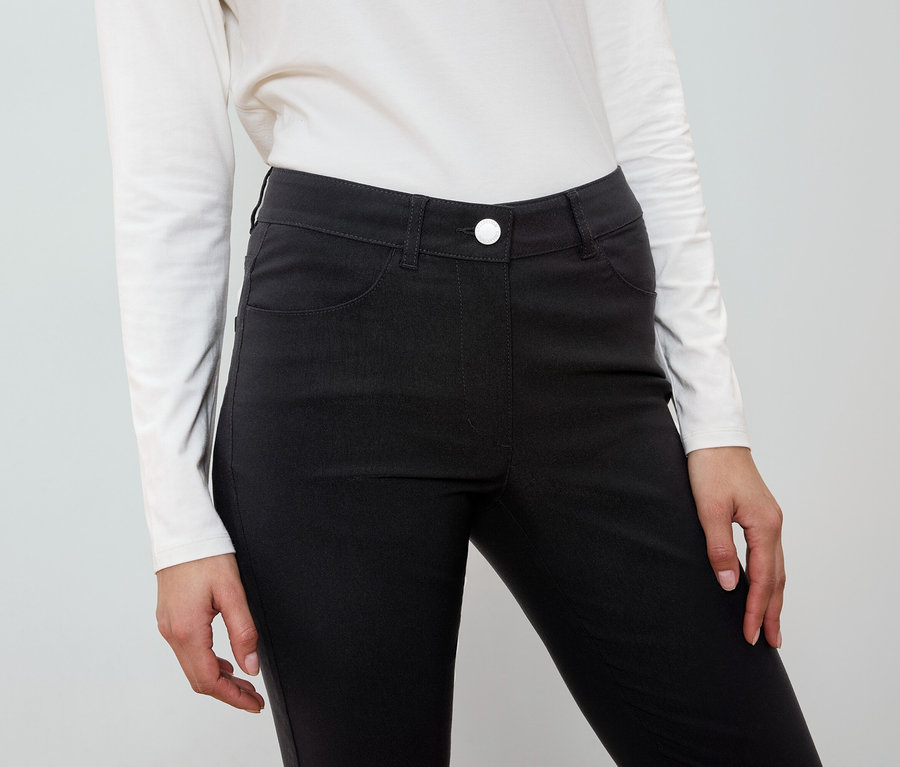 Žena má na sobě černé kalhoty a bílou košili.