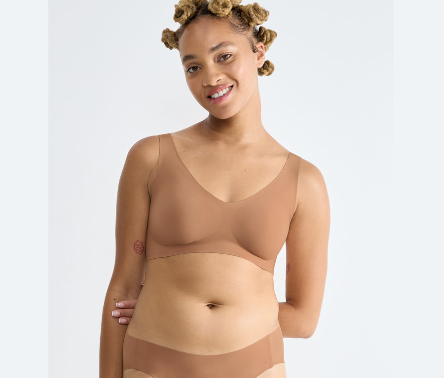 Žena má na sobě braletku Sloggi ZERO Feel 2.0 Bralette v nostalgické hnědé barvě a kalhotky.