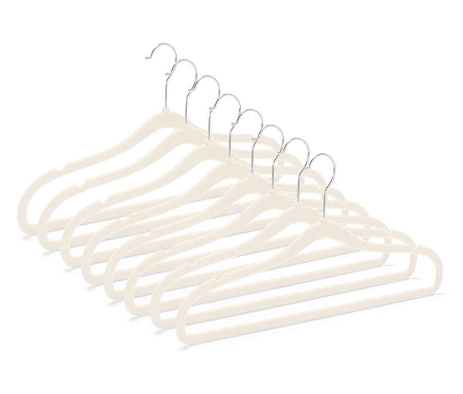 Sedm béžových sametových ramínek na oděvy s chromovanými háčky, uspořádaných diagonálně v pravém dolním rohu.