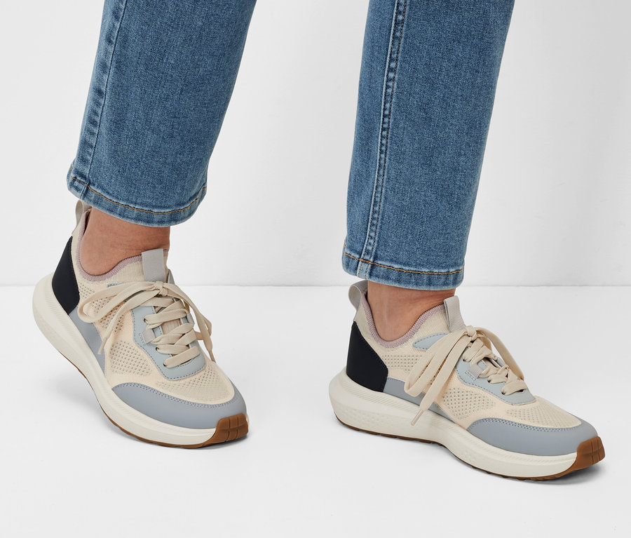 Nohy v džínových kalhotách a botách sneaker na bílém pozadí.