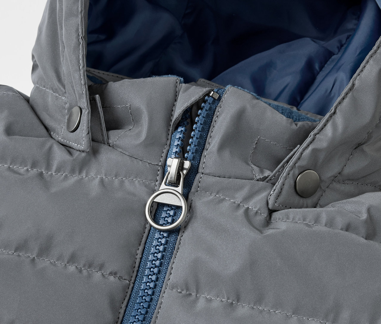 Detail šedé prošívané bundy Reflexní dětská prošívaná bunda s modrým zipem.