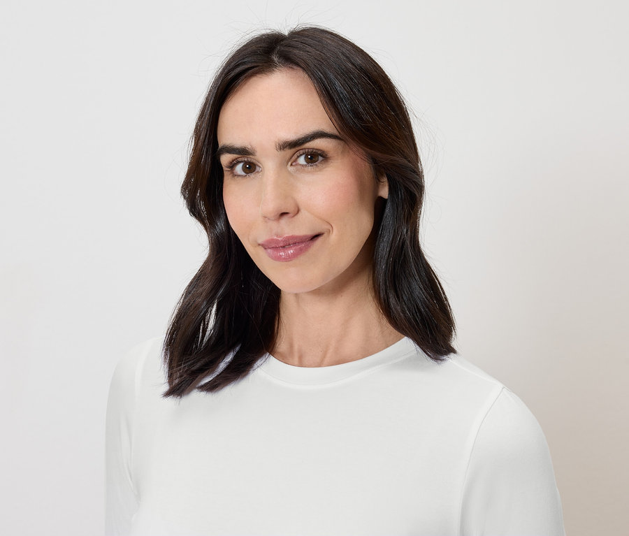 Portrét ženy s tmavými vlasy v bílém tričku.