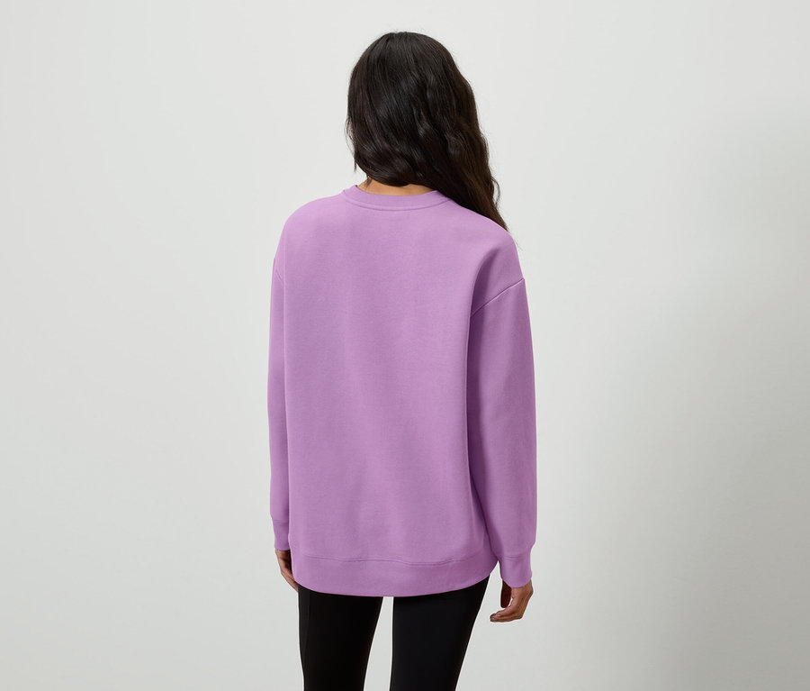 Zezadu je vidět žena s dlouhými tmavými vlasy v lila mikině a černých legínách.