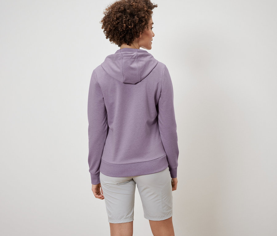 Zezadu je vidět žena s kudrnatými vlasy v mikině a šortkách.