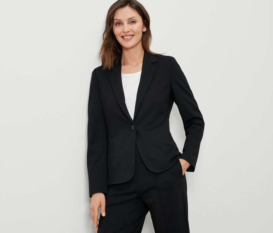 Žena má na sobě černý žerzejový blejzr.