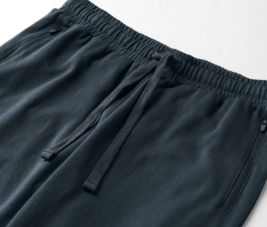 Detailní záběr na tmavě modré tepláky se stahovací šňůrkou a kapsami na zip.