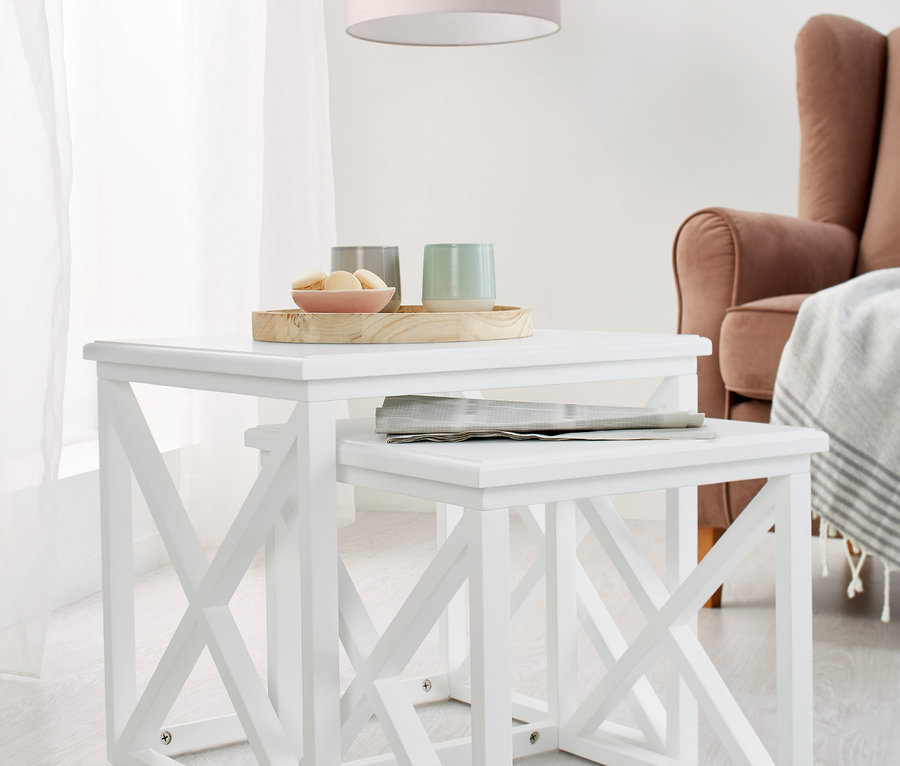 Dva bílé odkládací stolky, jeden zasunutý pod druhým.