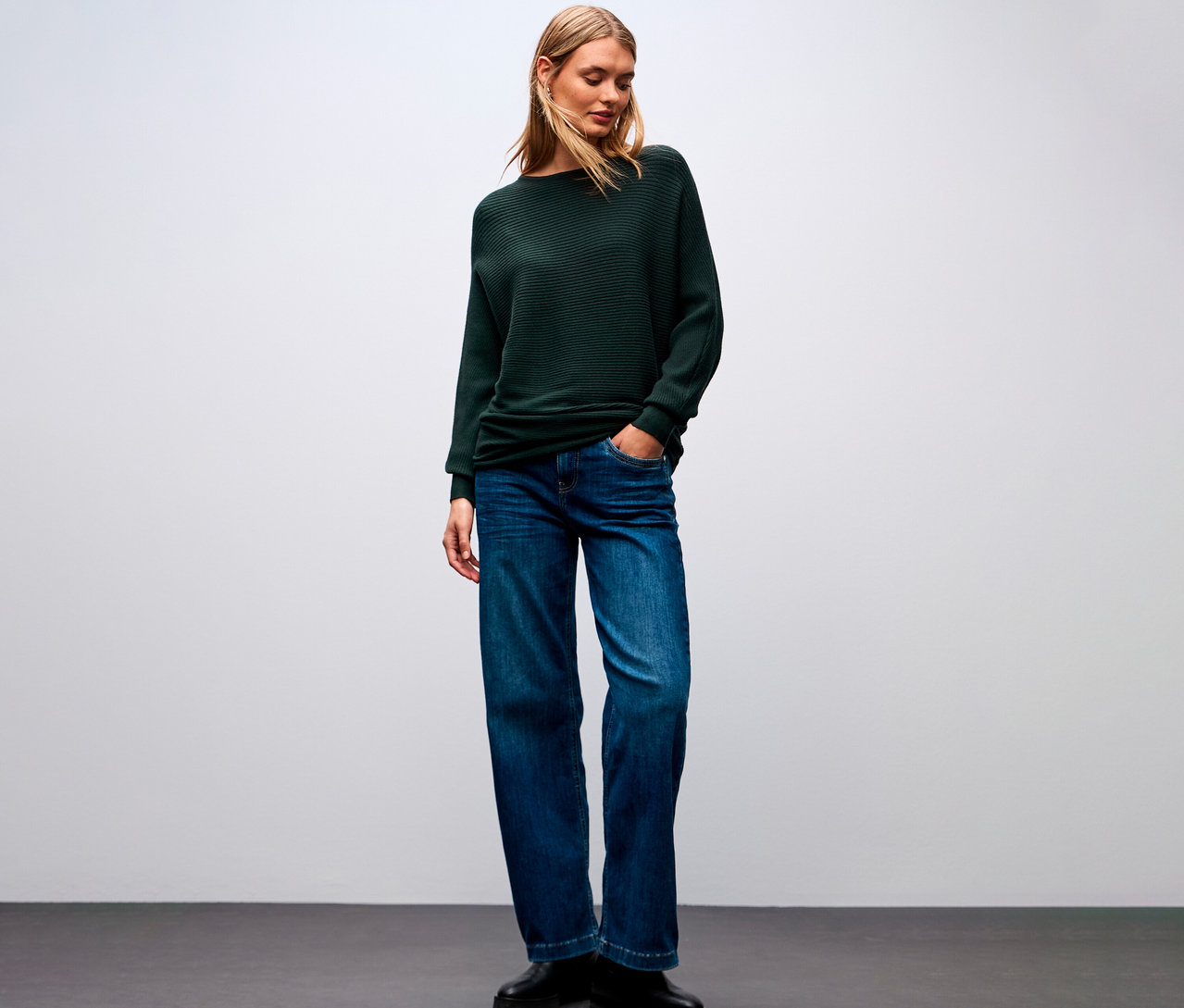 Žena má na sobě strukturovaný svetr Street One, džíny a boty.