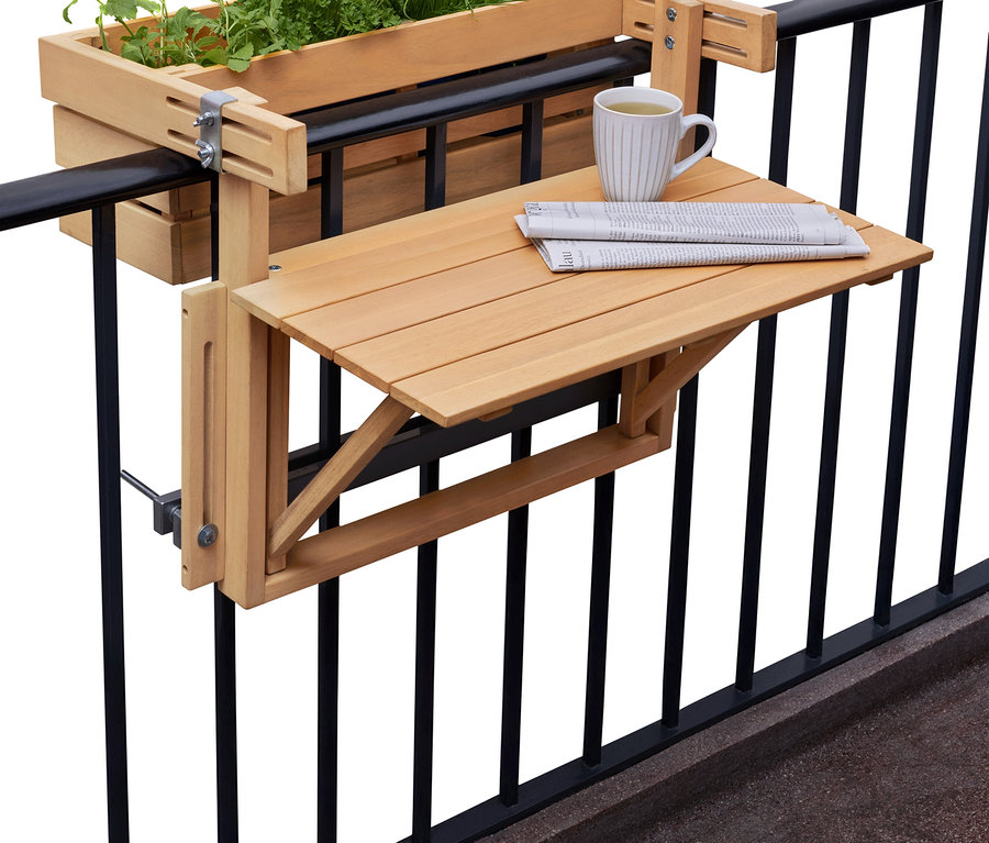 Květináč s bylinkami a skládací stolek s novinami a šálkem visí na černém balkonovém zábradlí.