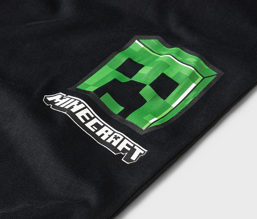 Detailní záběr na černé oblečení se zeleným motivem Minecraft Creeper.