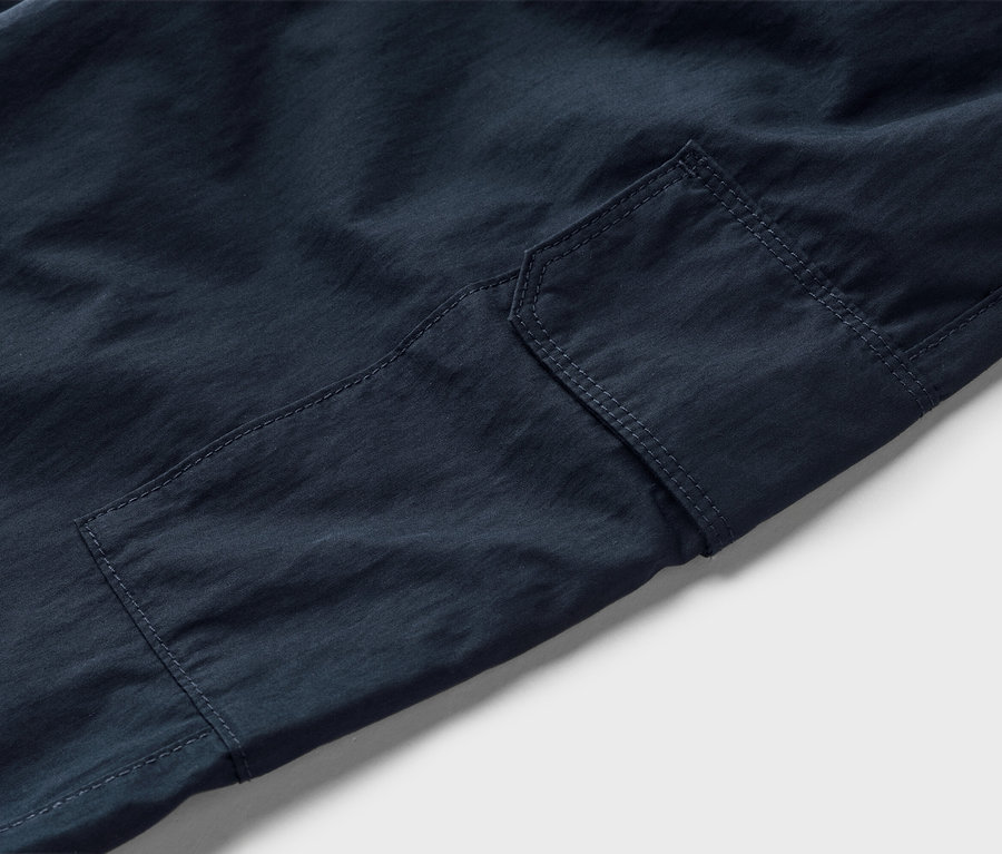 Detail tmavě modrých cargo kalhot s našitou kapsou.