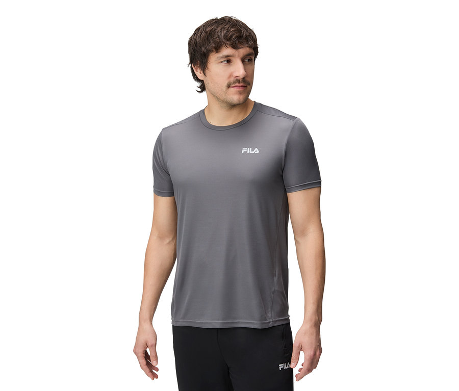 Muž má na sobě šedé tričko Fila a černé kalhoty.