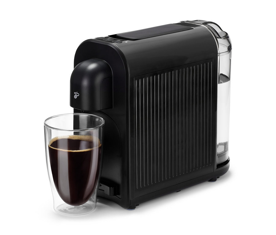 Černý kávovar Cafissimo now black vedle sklenice s kávou.