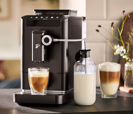 Automatický kávovar »Esperto 2 Milk« Granite Black připravuje kávu do sklenice. Vedle stojí karafa na mléko.
