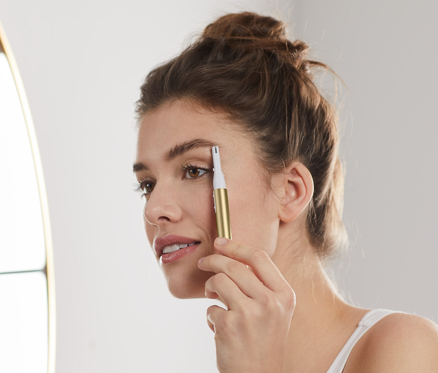 Žena si upravuje obočí elektrickým zastřihovačem obočí.