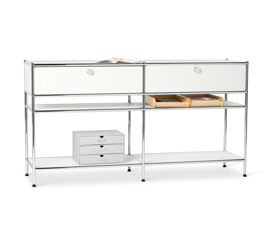 Dva bílé kovové konzolové stolky »CN3« se 2 zásuvkami stojí vedle sebe. Na horní straně stolku leží kniha.