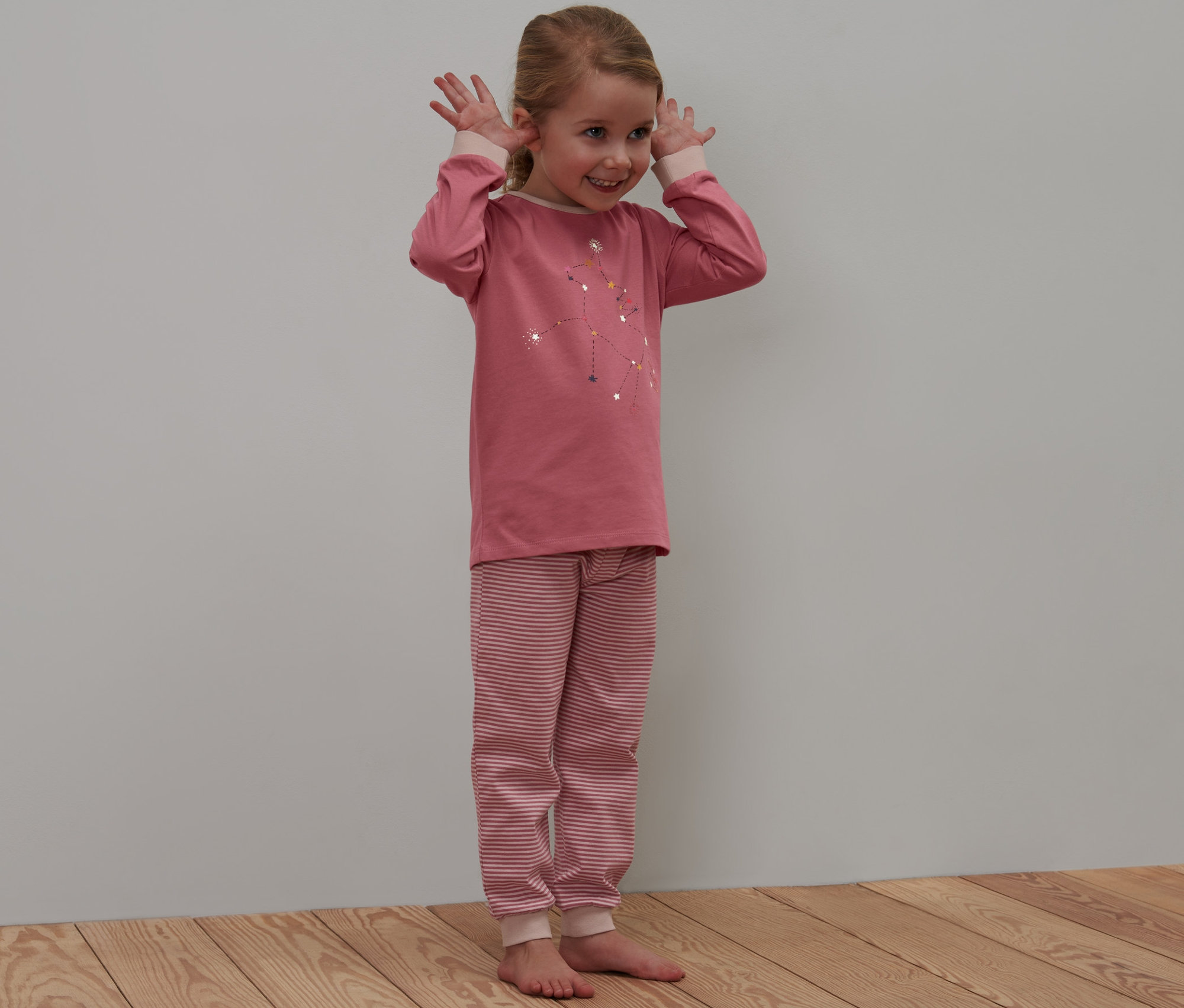 Dívka pózuje v dětském pyžamu s motivem jednorožce, které svítí ve tmě.