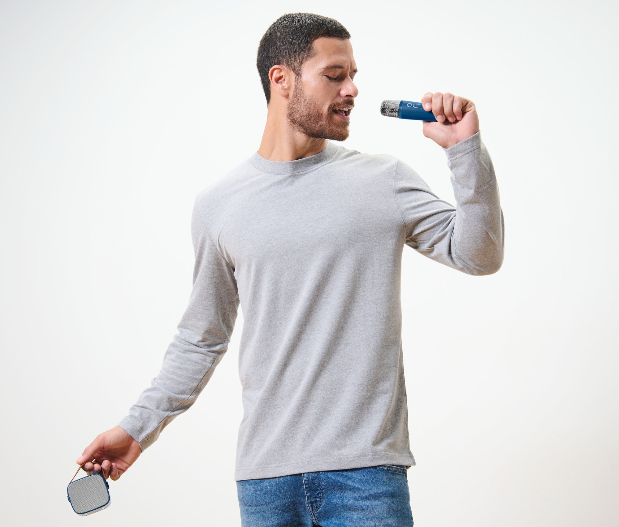 Muž zpívá do mikrofonu ze sady na karaoke s reproduktorem.