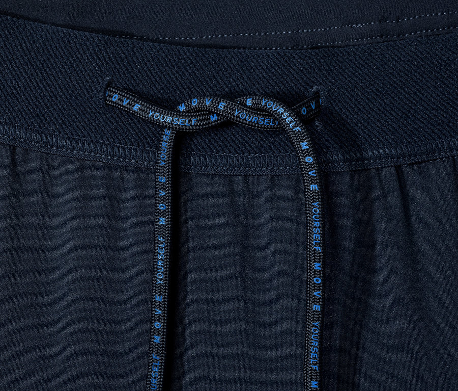 Detail námořnicky modrých sportovních šortek se stahovací šňůrkou.